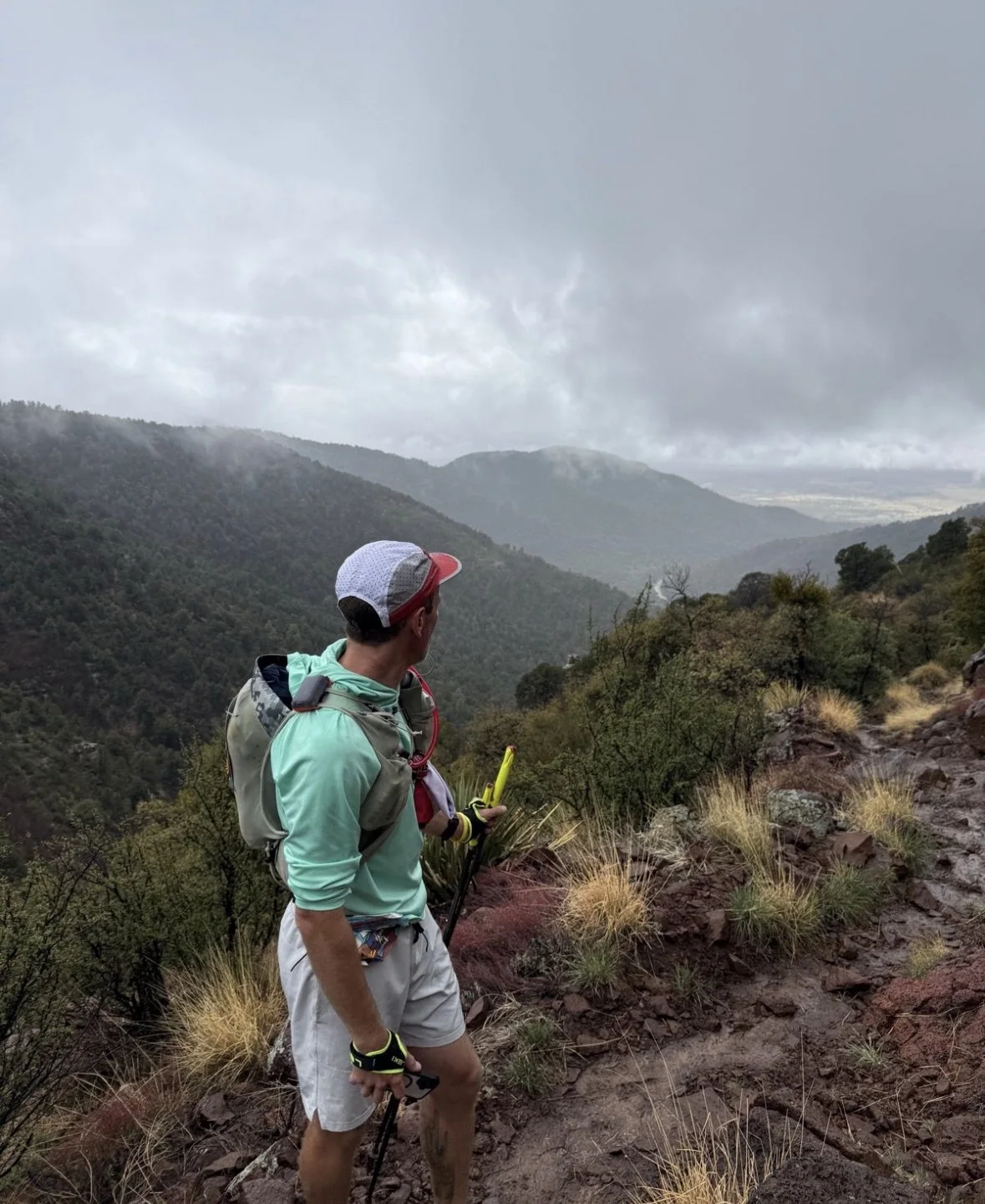 Josh Frewin on a misty mountain trail carrying trekking poles